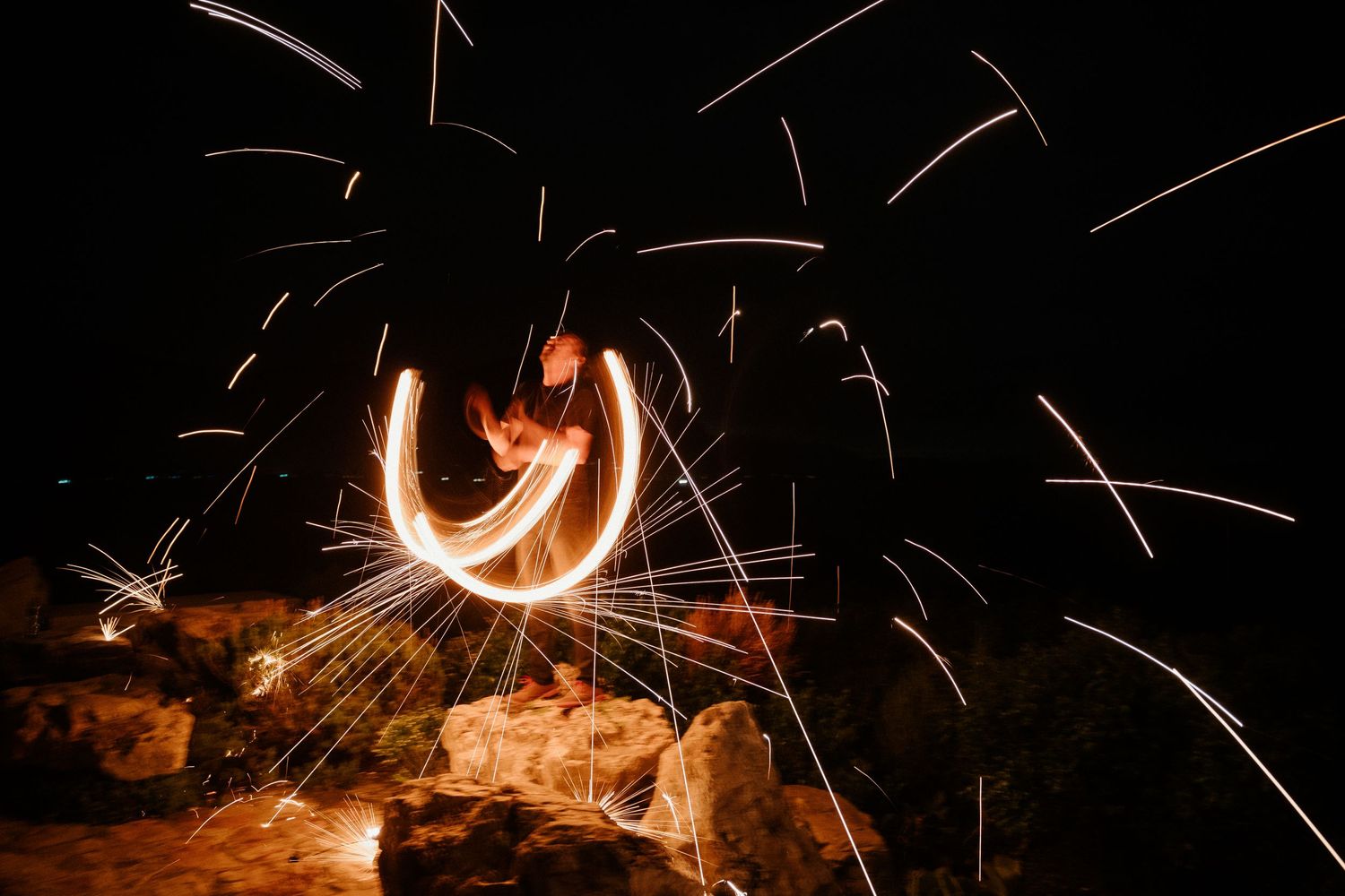 Long exposure photograph of fire spinning creating circular light trails against a dark background.