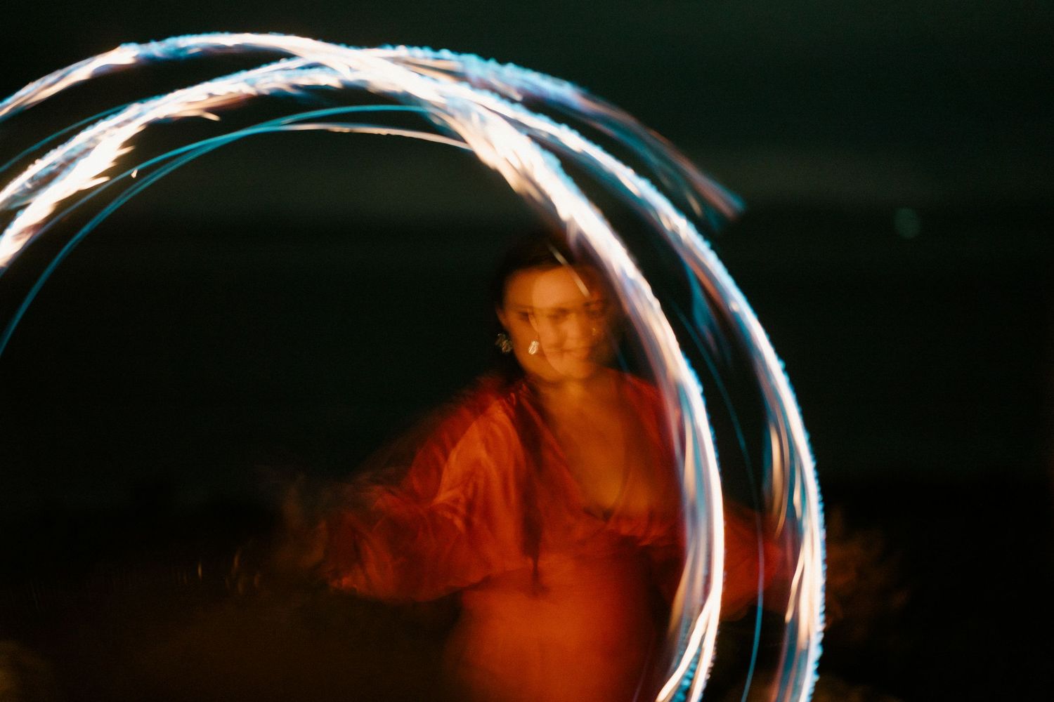 Colorful light painting performance with blue and red streaks in a dark setting.
