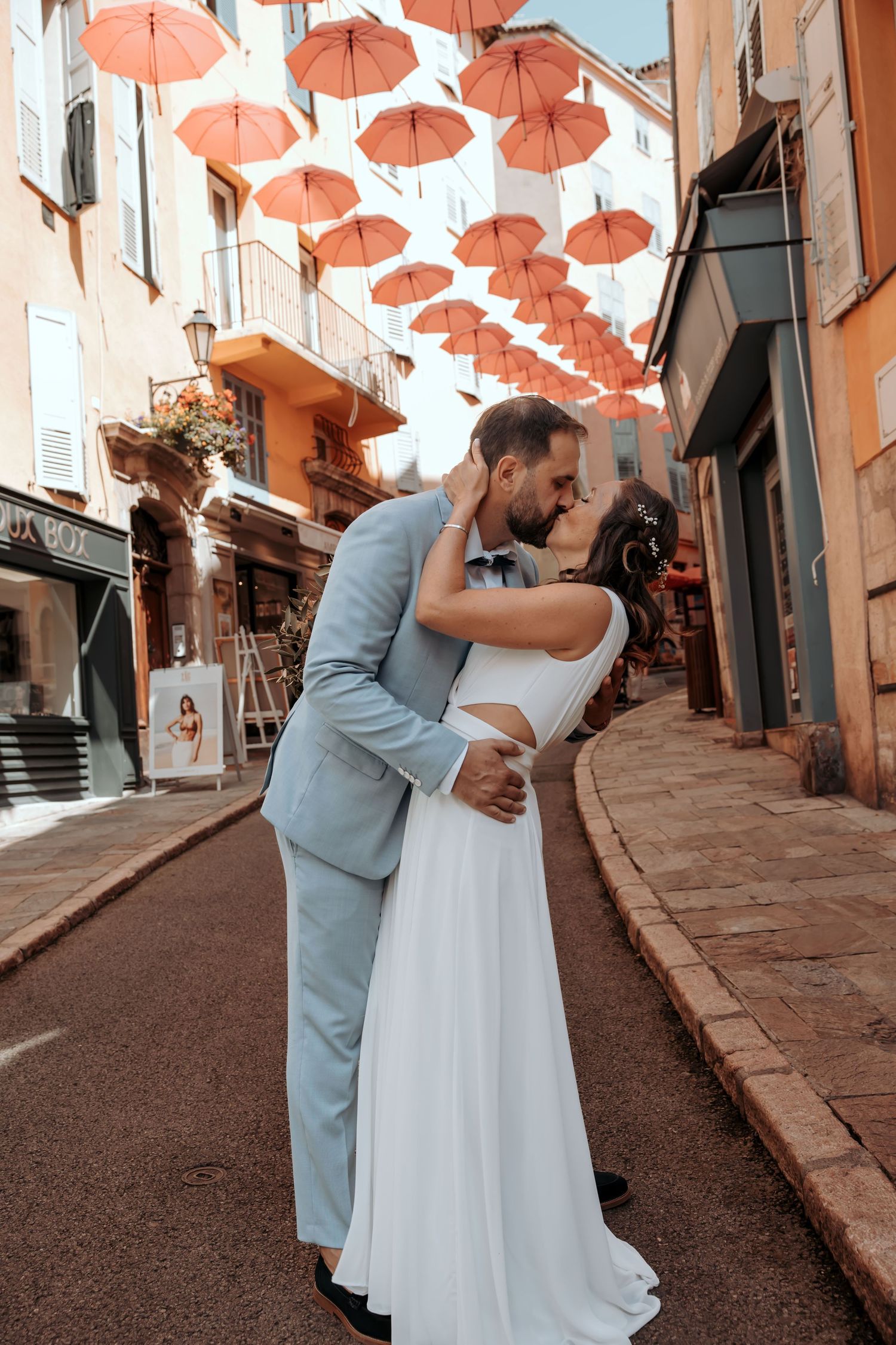 Wedding couple dancing under canopy of orange umbrellas in charming European street.