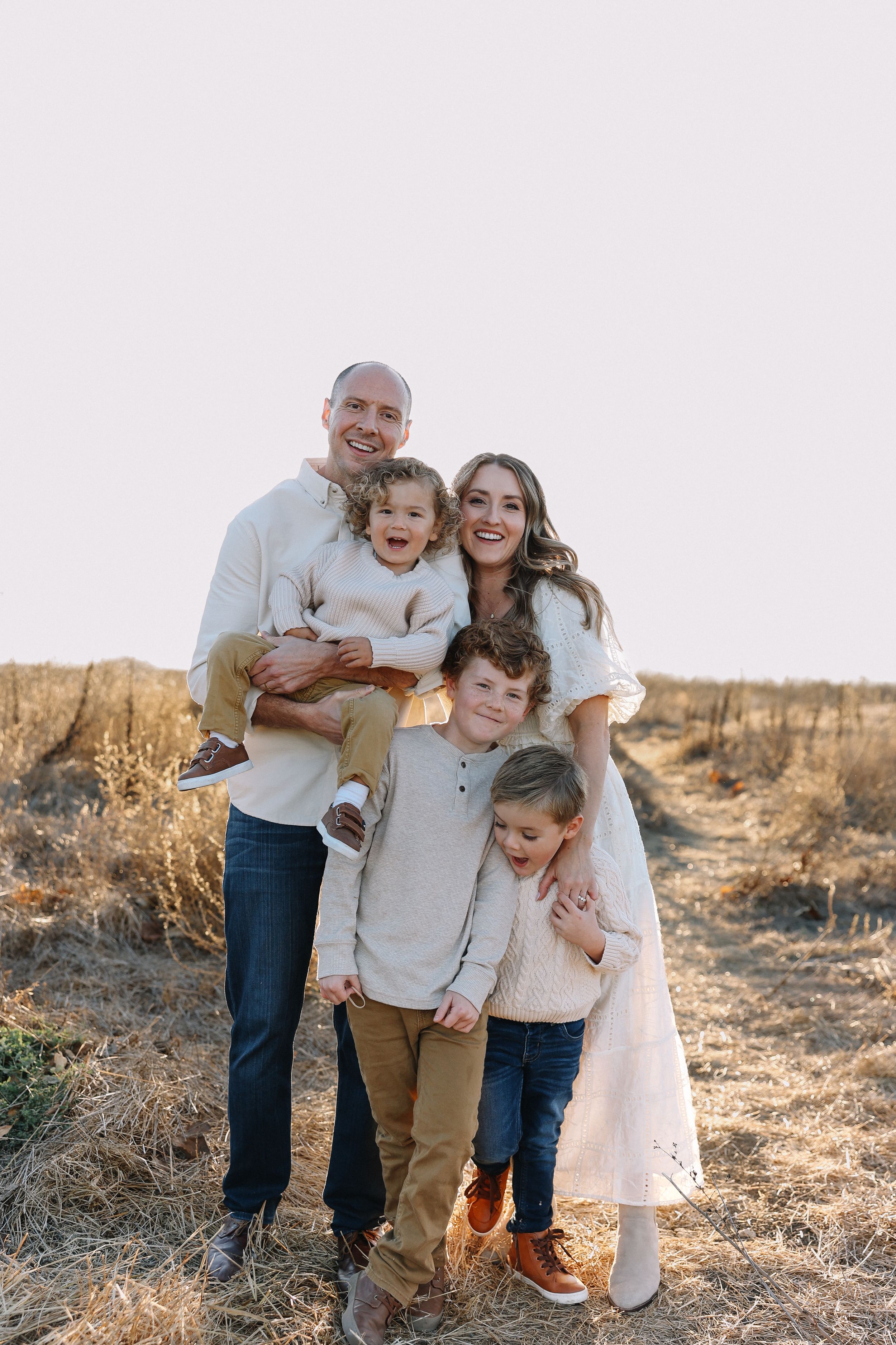 Natural family portrait in a golden California field at sunset