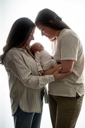 Two people in casual clothing tenderly holding and looking down at a newborn baby in a heartwarming moment.