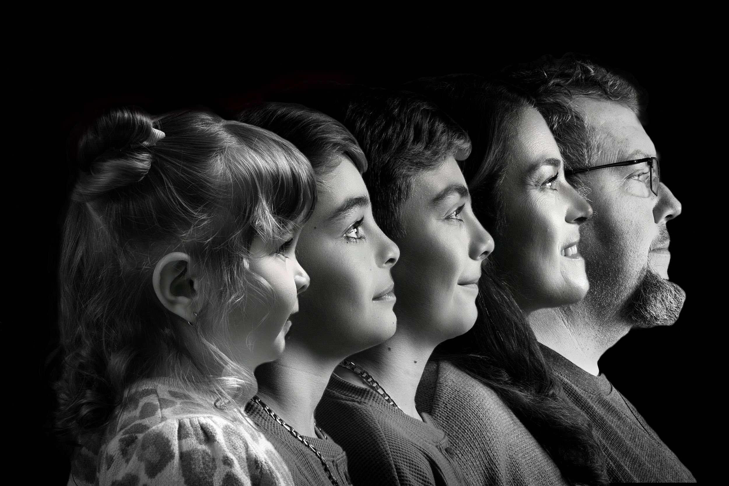 Black and white profile portrait of a family of four arranged in ascending height order looking sideways.