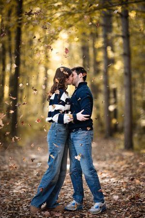 A romantic autumn scene in the woods with falling leaves and golden sunlight filtering through the trees.