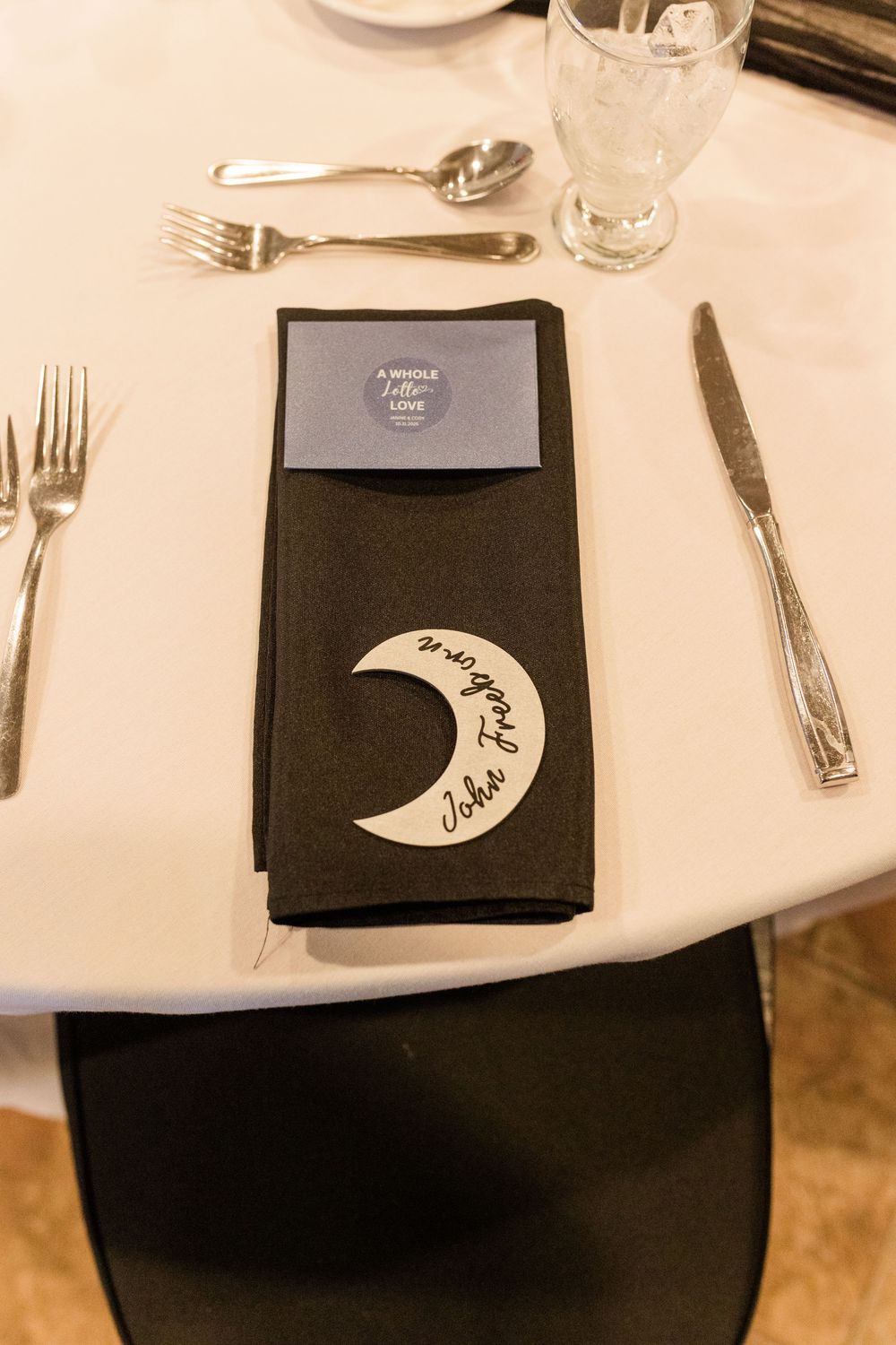 Place settings at an elegant restaurant with black napkins and white tablecloths.