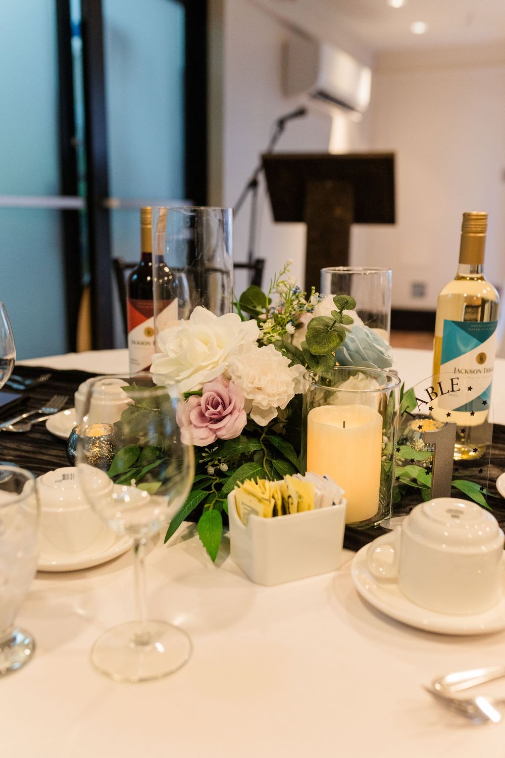 Elegant wedding reception table setting with glowing candles and delicate floral arrangements in white and pink.