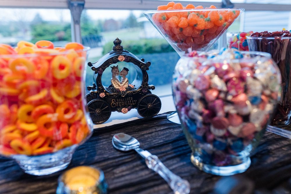 A colorful assortment of fresh fruit and snacks displayed in glass bowls at an outdoor waterfront party setting.