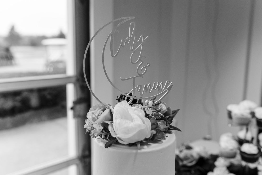 A black and white photo of a wedding cake topper with a crescent moon design and floral decorations.