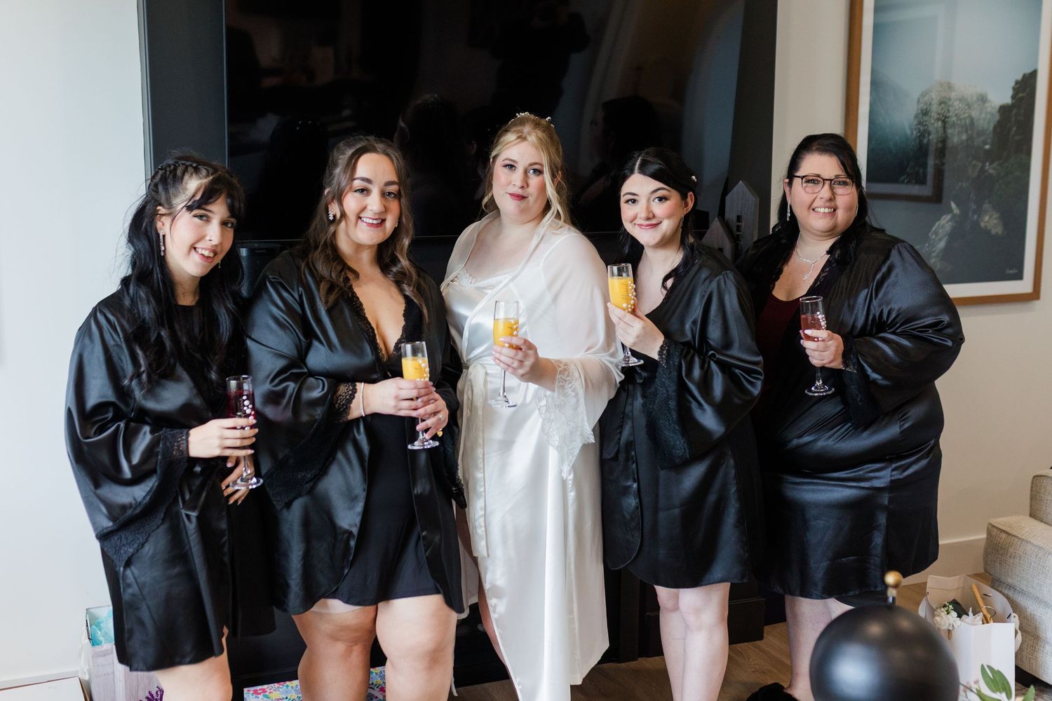 A group in matching black jackets poses together while holding drinks at a celebration event.