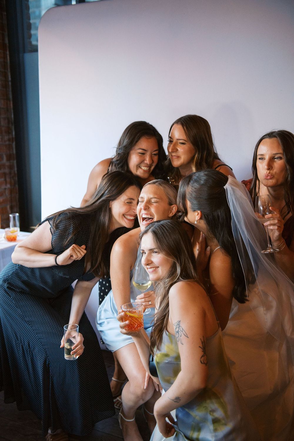 A group of friends sharing joyful moments and laughter at a social gathering with drinks.