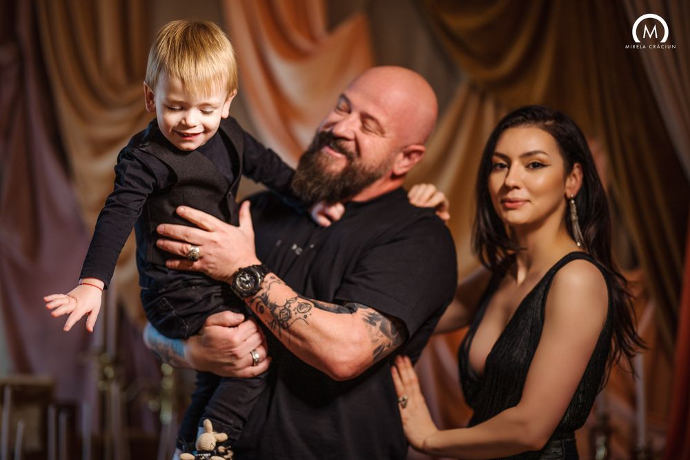 A couple shares a tender dance moment with their young child at a wedding reception.