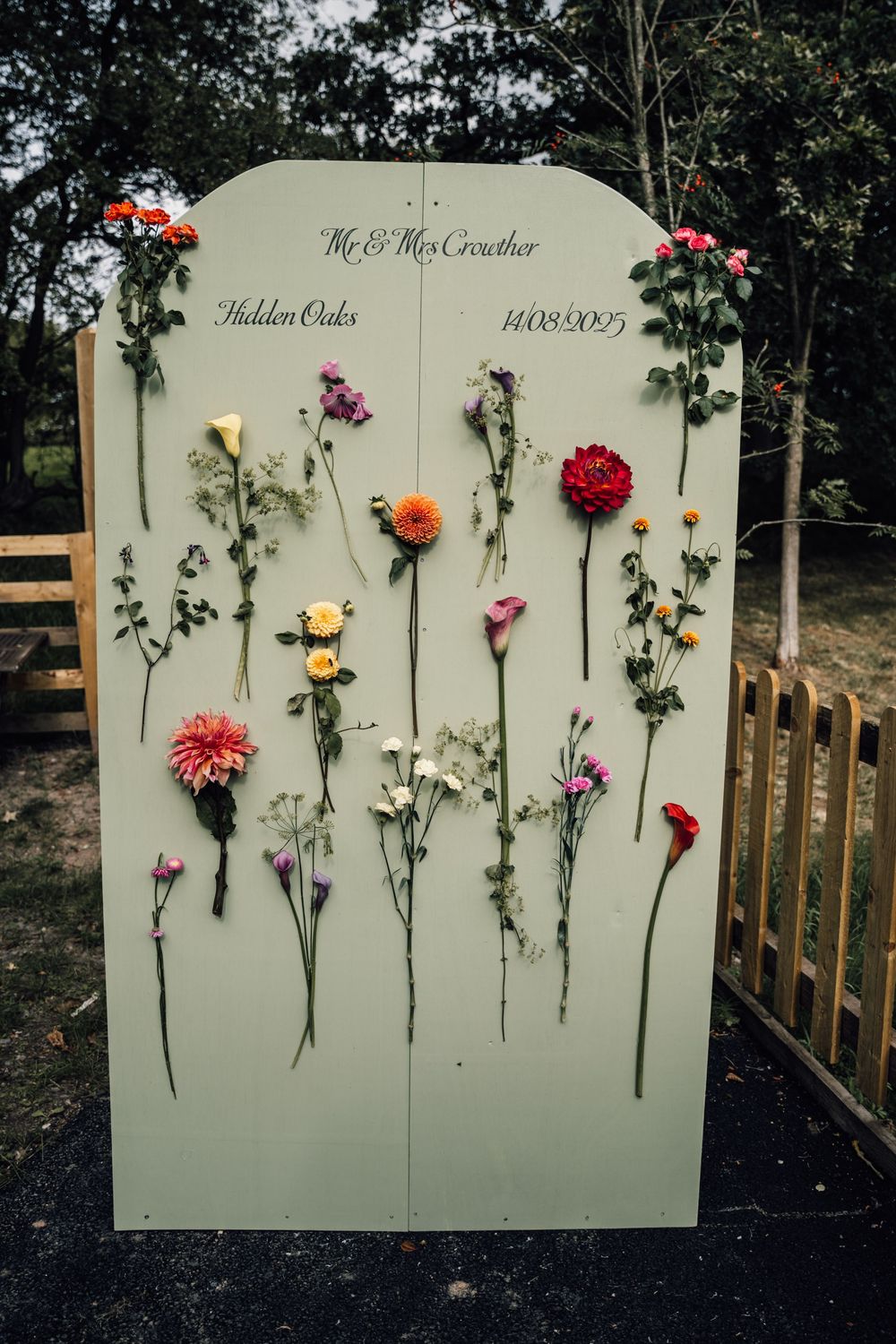 Decorative wall display with colorful fresh flowers arranged on a pale backdrop.