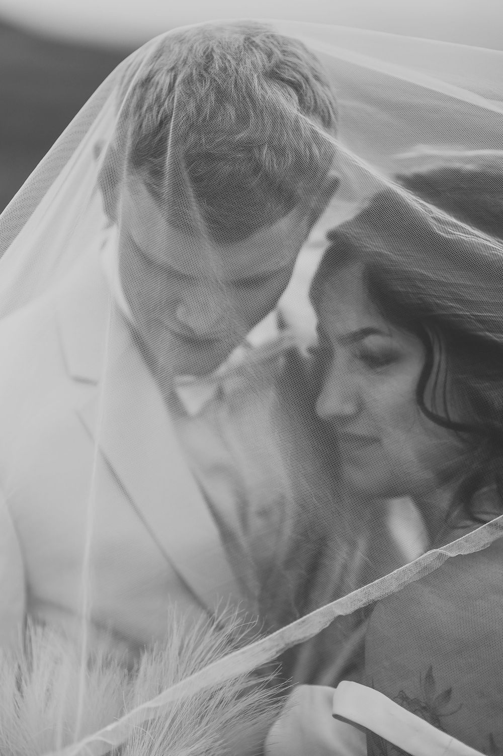 A romantic black and white photo series of a couple sharing intimate moments under a wedding veil.