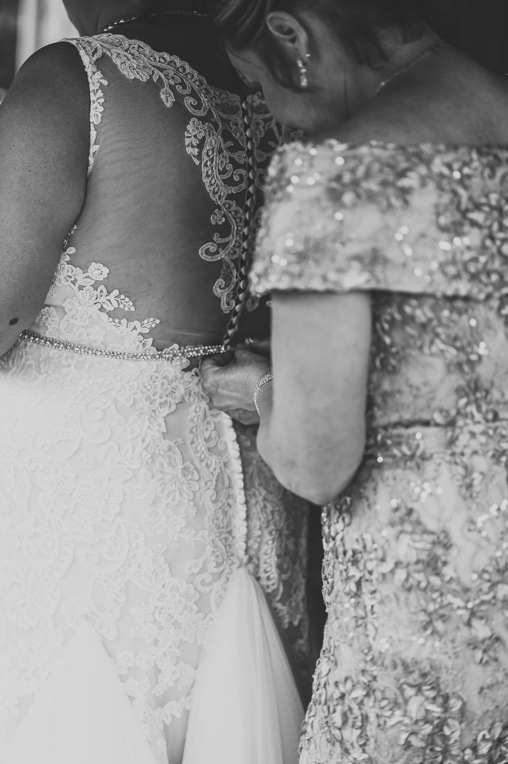 Black and white detail of intricate lace wedding dresses showing delicate beading and embellishments.