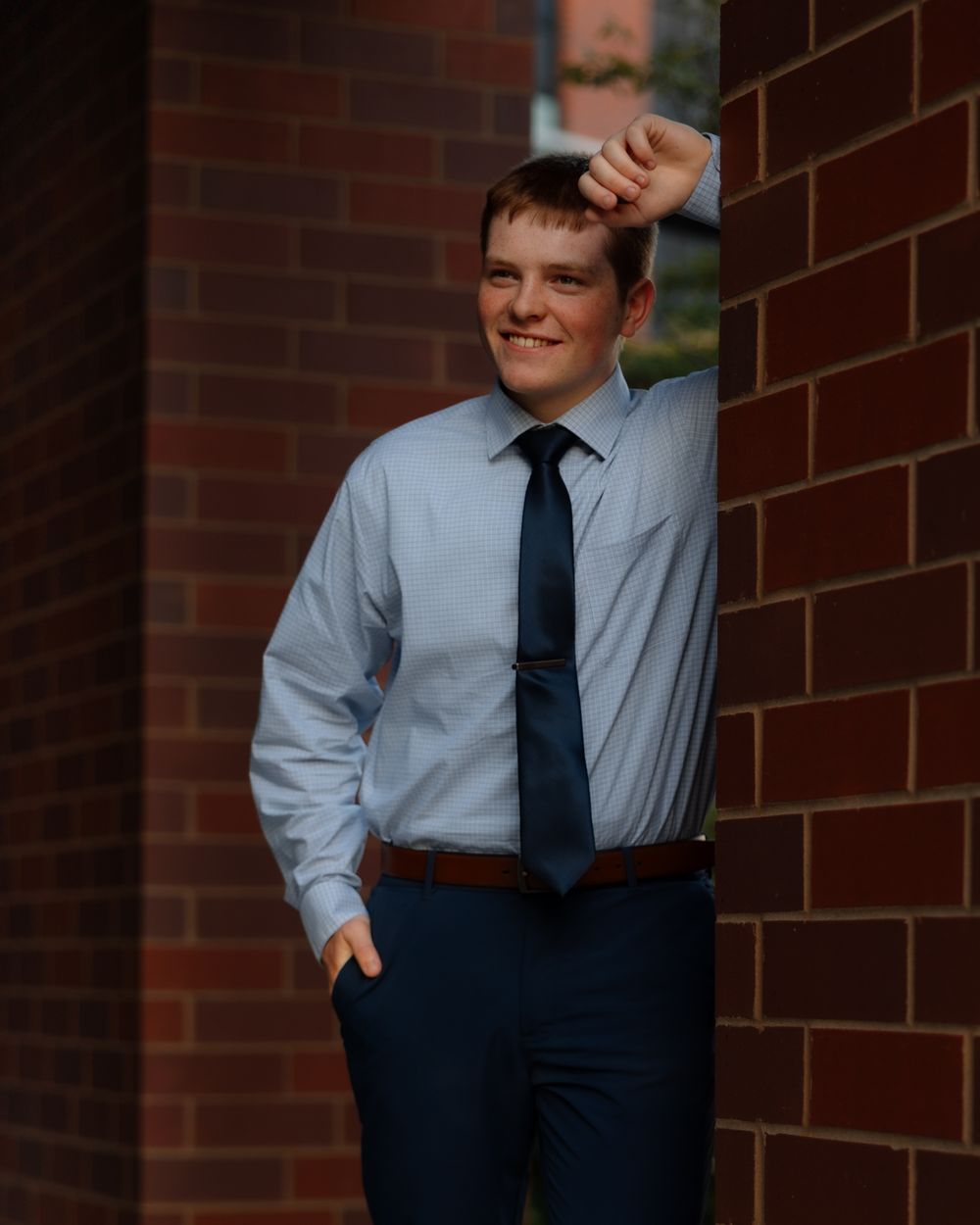 A man in business attire stands against a brick wall in a series of casual poses.