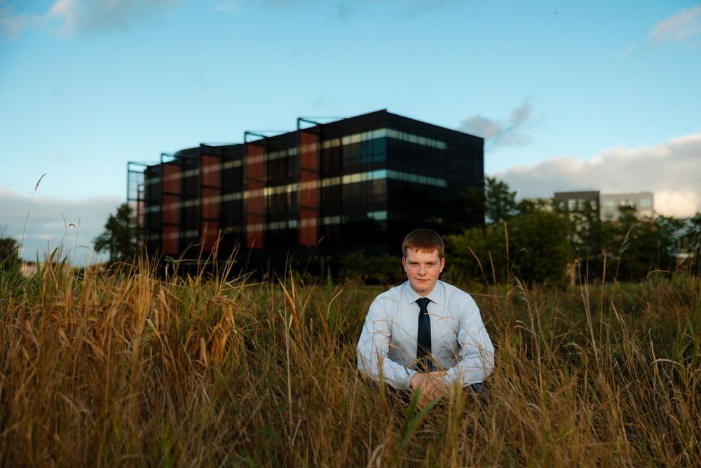 Modern office building exterior with tall grass in foreground against blue sky at sunset.