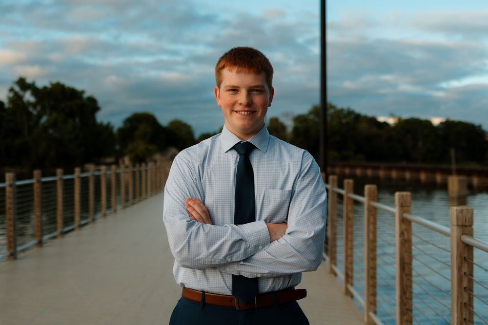 Professional portrait session at sunset on a wooden boardwalk overlooking a scenic waterfront.