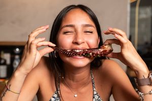 Person smiling while taking a big bite of food.
