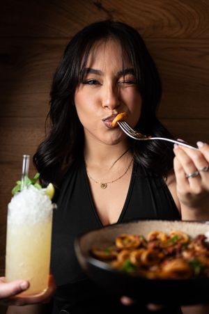 Dining scene with cocktails and food in dramatic lighting.