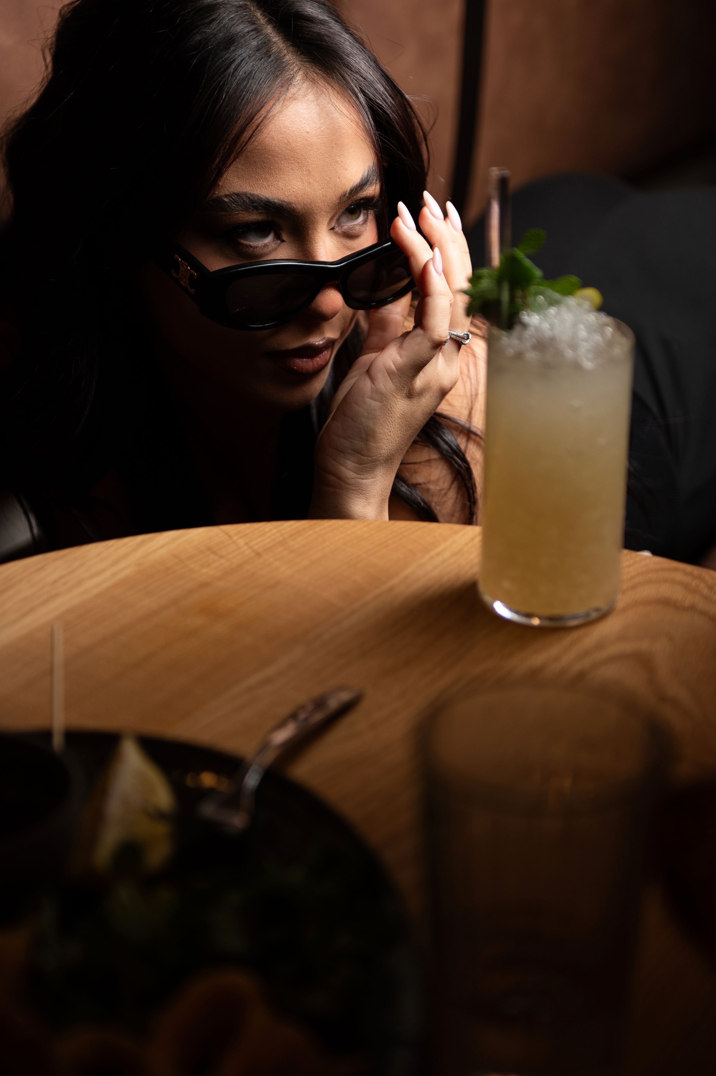 Moody low-light photo of a dining table with a cocktail glass.