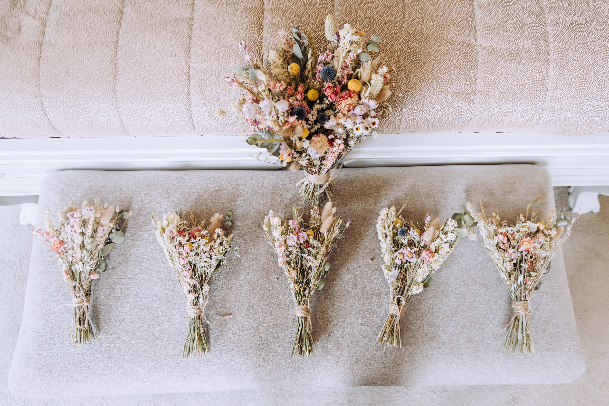 Beautiful dried flower wedding bouquets in pastel colors arranged on white linen.