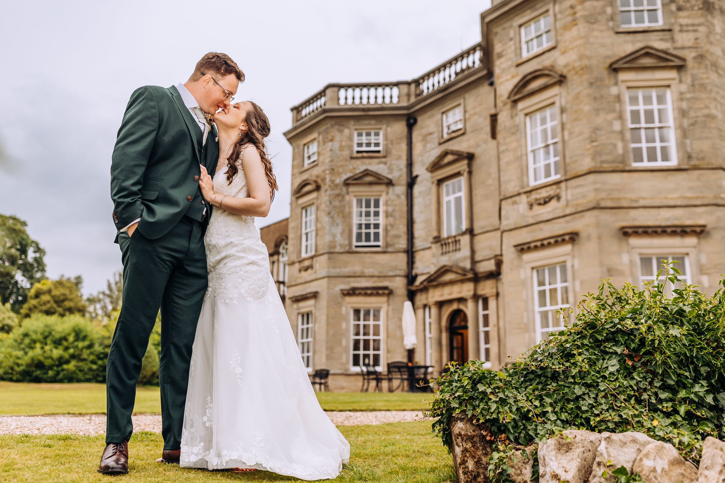 Newlyweds pose for romantic portraits outside a grand historic stone mansion.