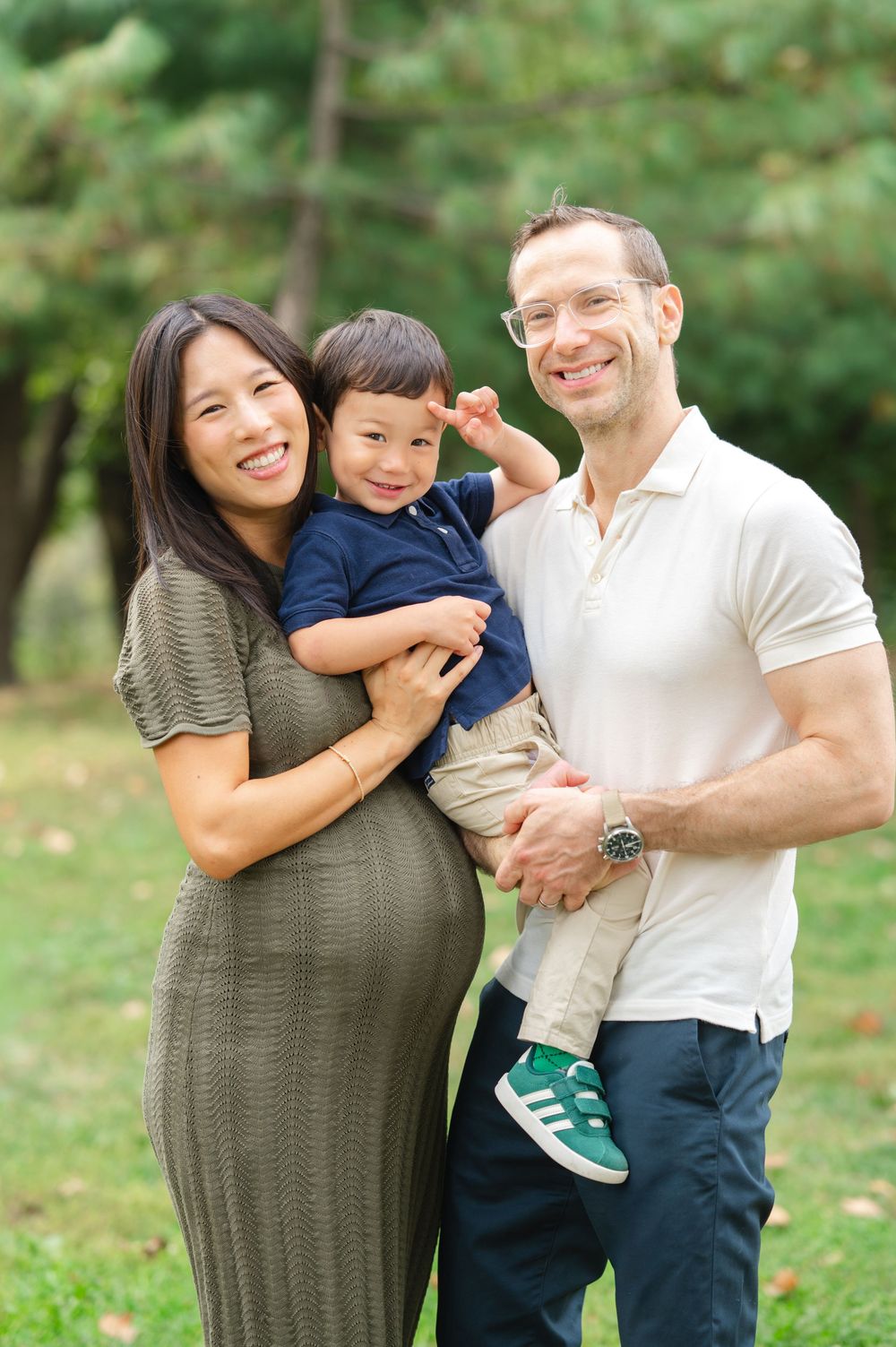 A joyful family plays and embraces outdoors in a Central Park on a sunny fall day for a family portrait.