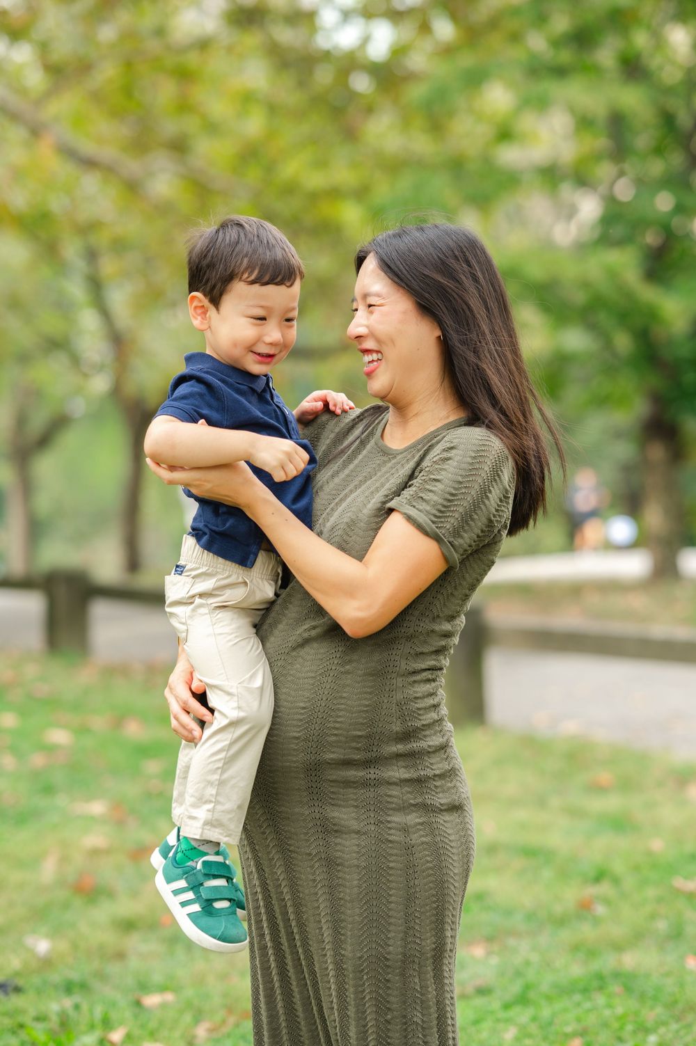 A mother and child share joyful moments together while playing outdoors in Central Park during a family portrait session.
