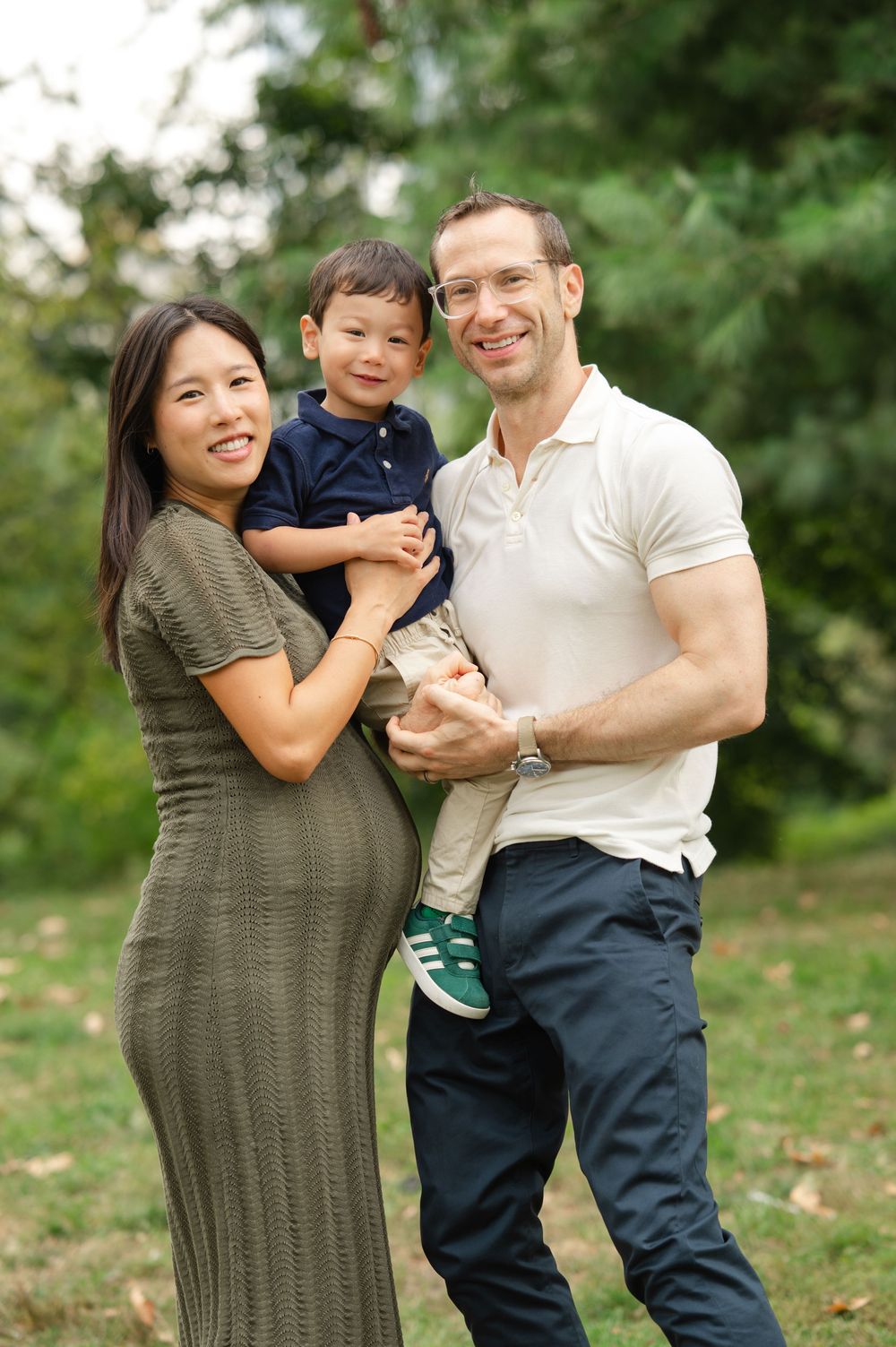 A family shares joyful moments together while posing outdoors in a natural setting with trees in the background.