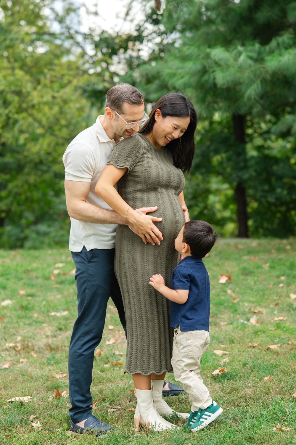 A little boy kisses his mother's pregnant belly during a family photoshoot in Central Park
