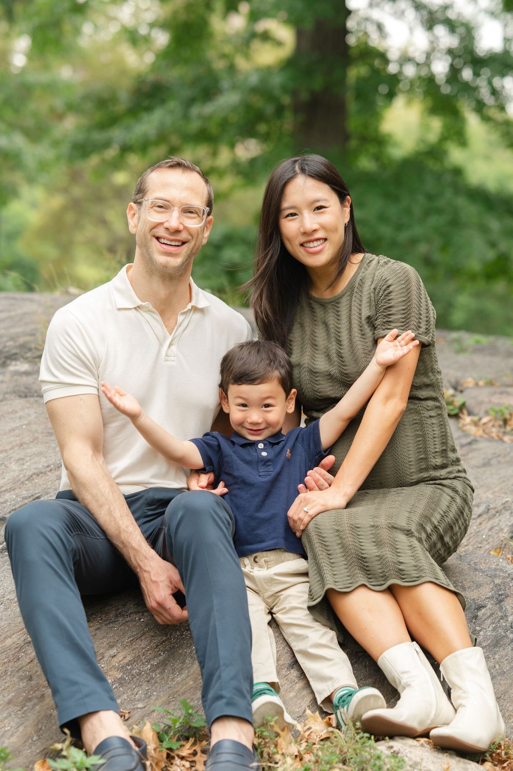 A family sits together on a rock in Central Park during a casual family photo session.