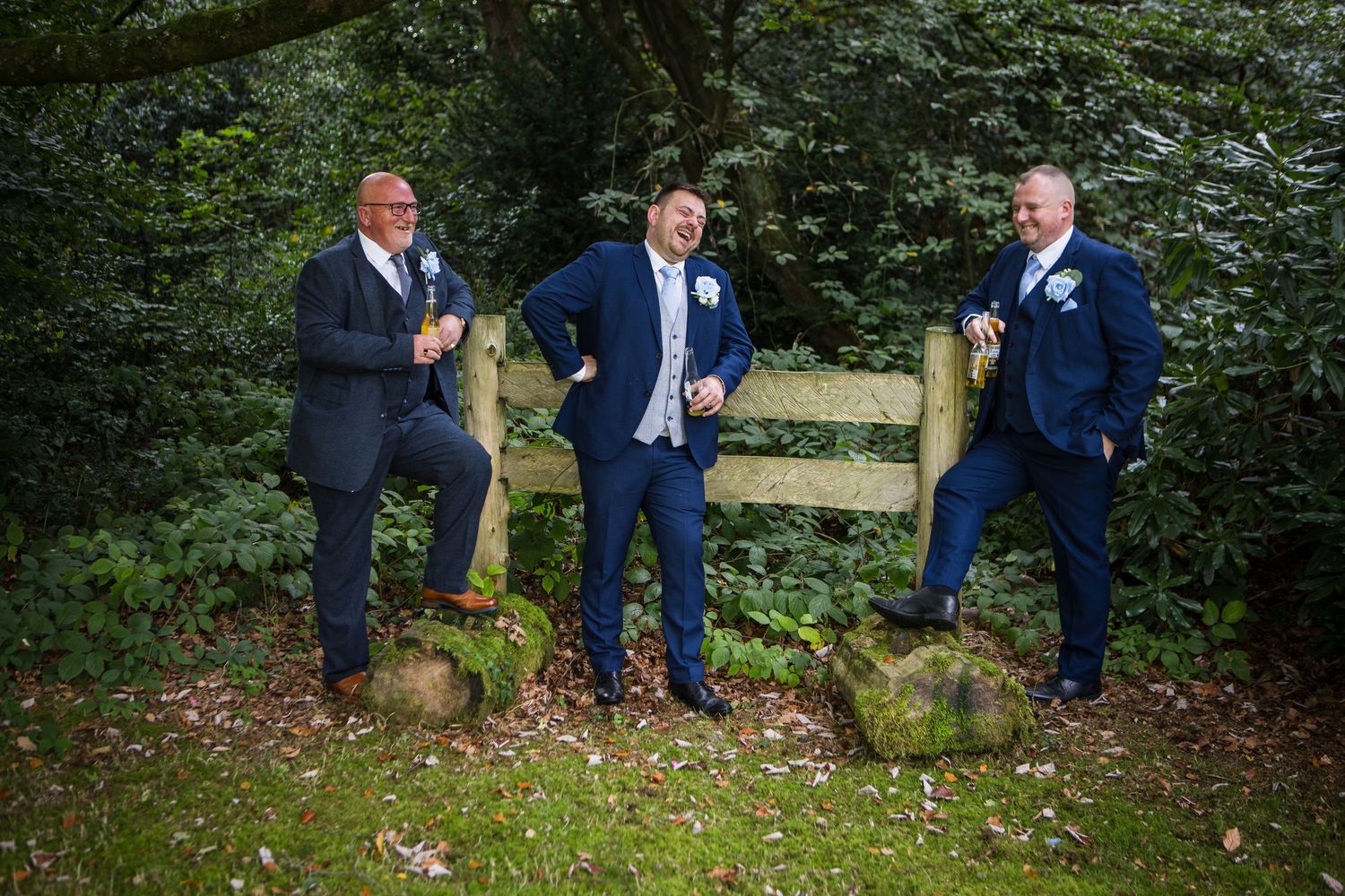 A sequence of photos showing groomsmen in navy suits posing playfully on a log in a wooded outdoor setting.