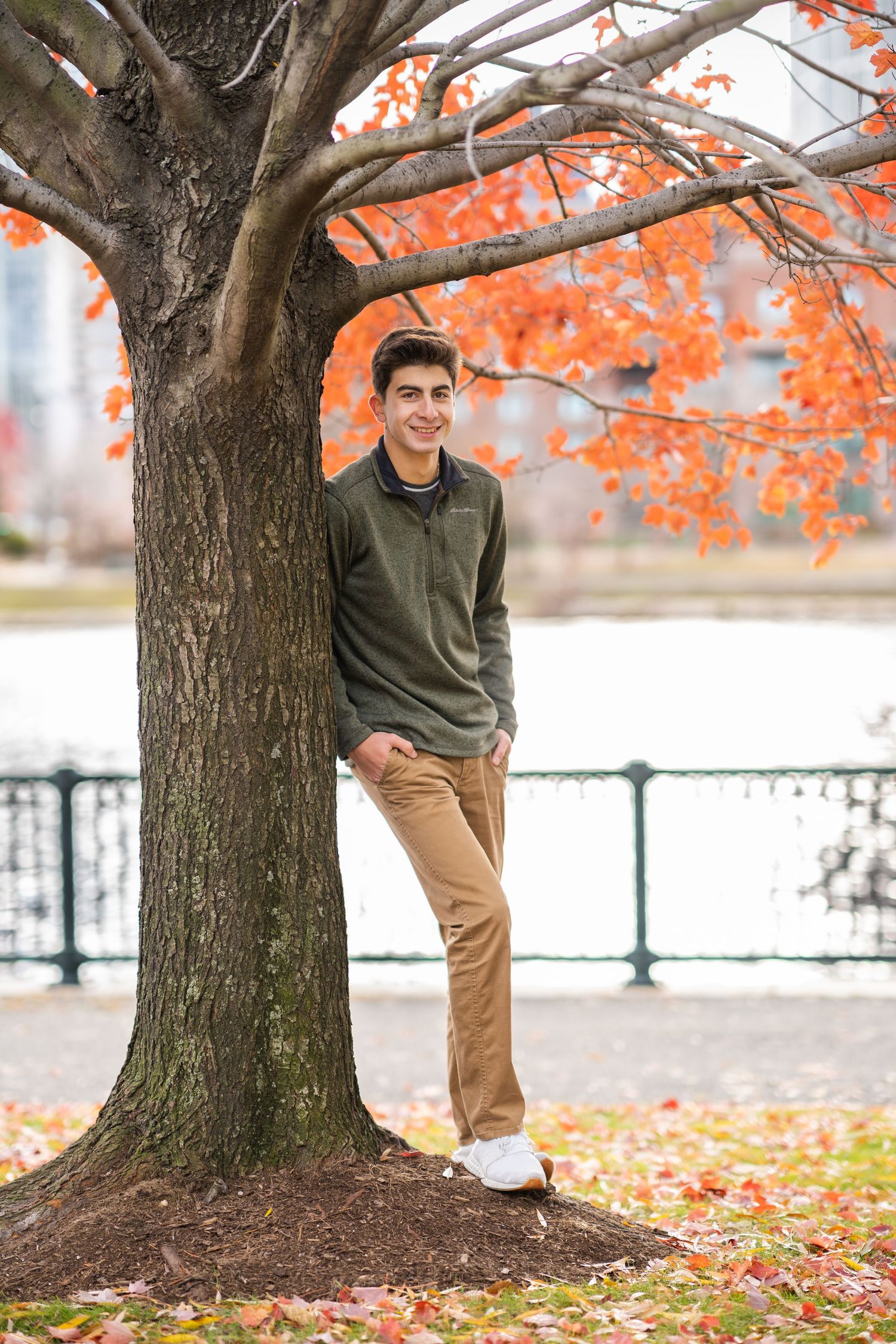 Four photos of someone posing next to a tree with vibrant orange autumn leaves in an outdoor park setting.