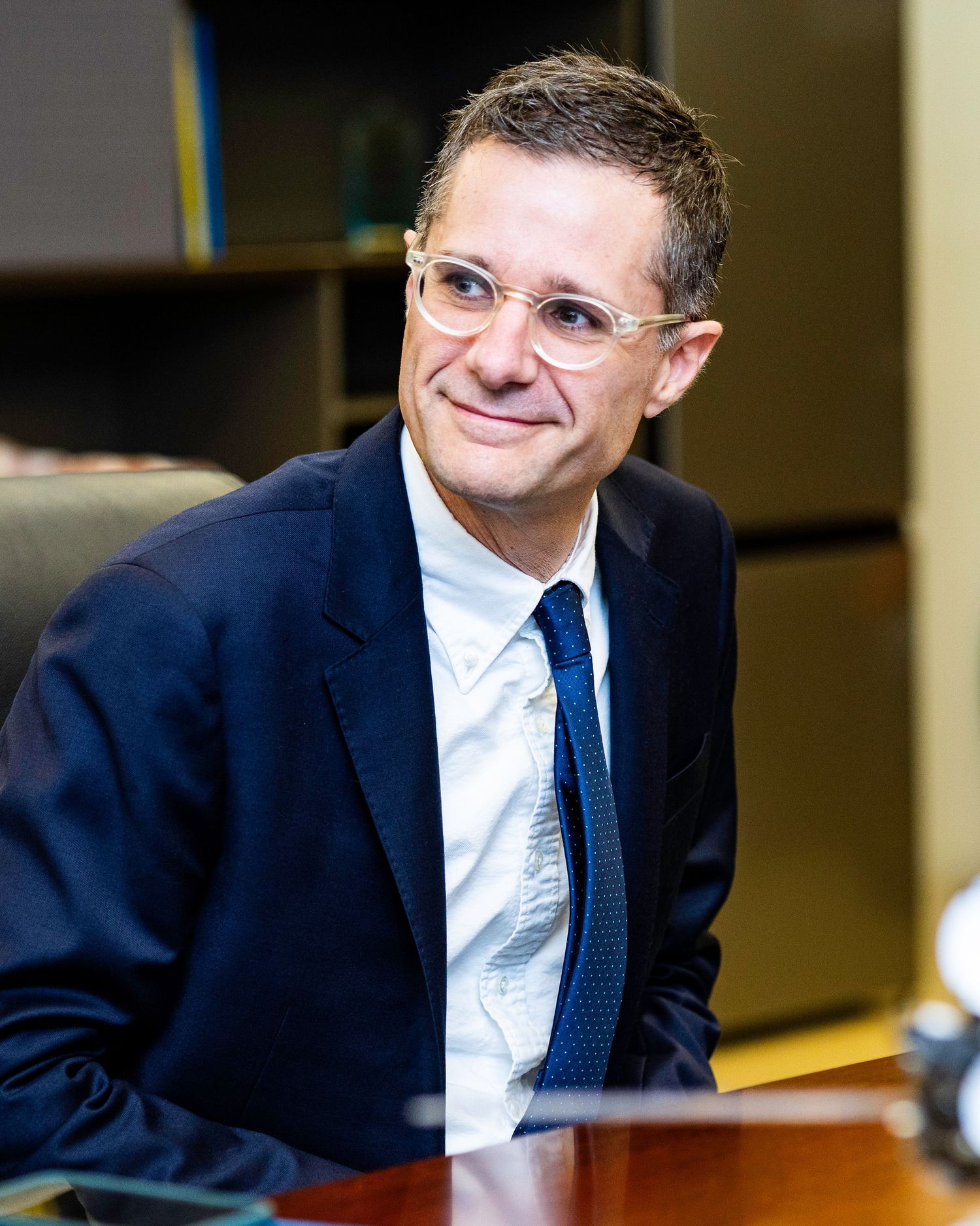 Professional in navy suit and tie during a business meeting.