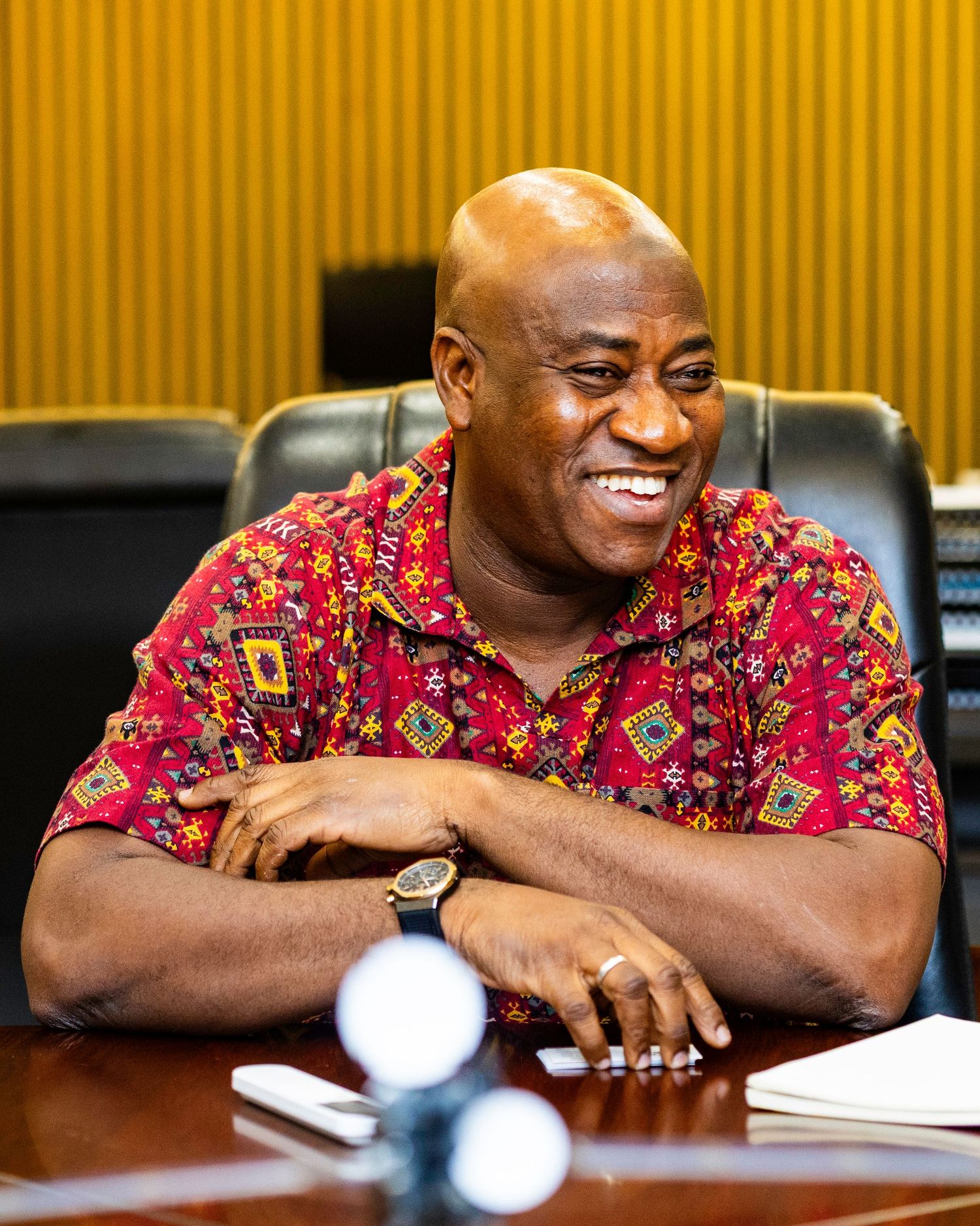 Person in vibrant red floral shirt smiling during a business meeting.