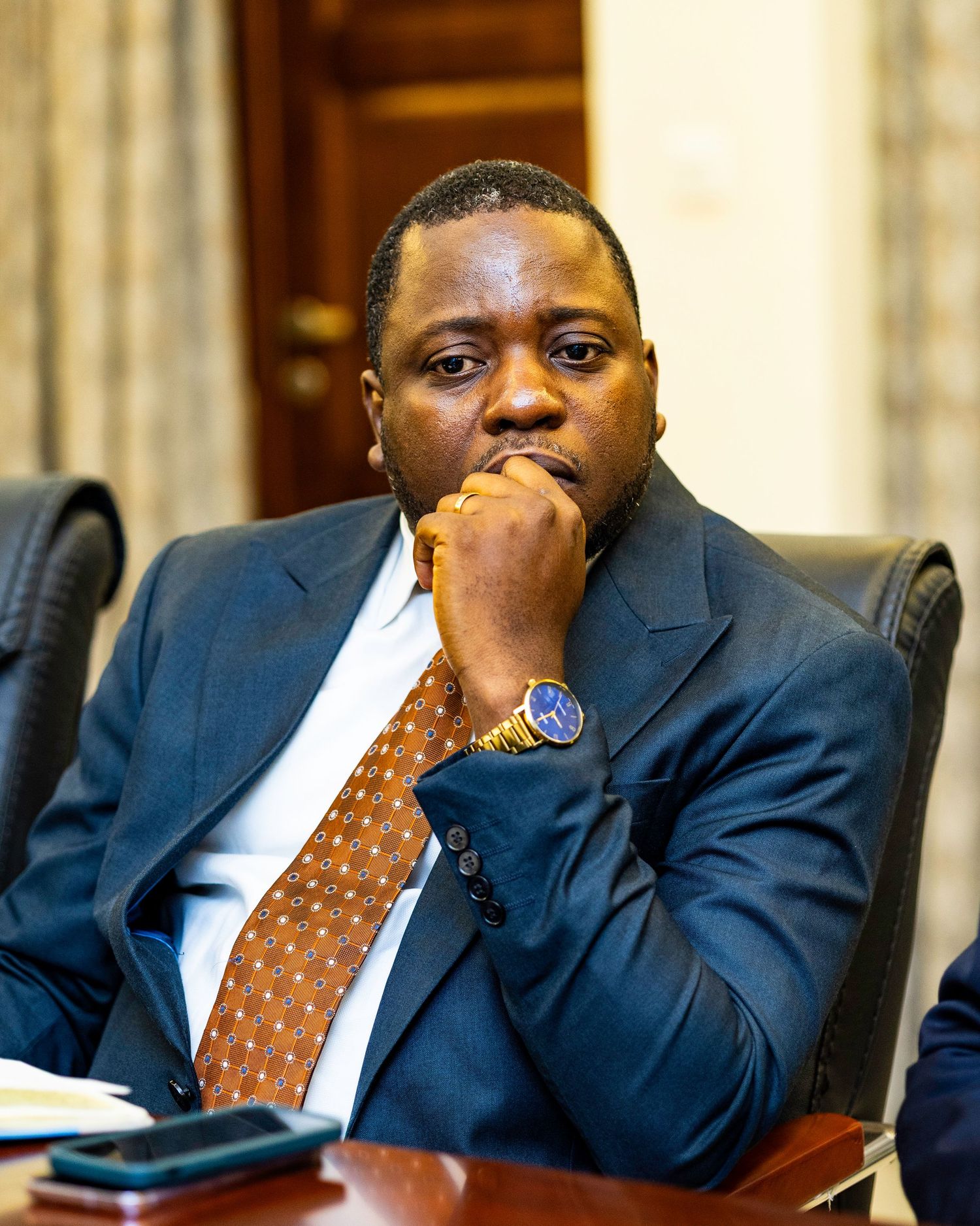 Professional in dark suit and polka dot tie during a business discussion.