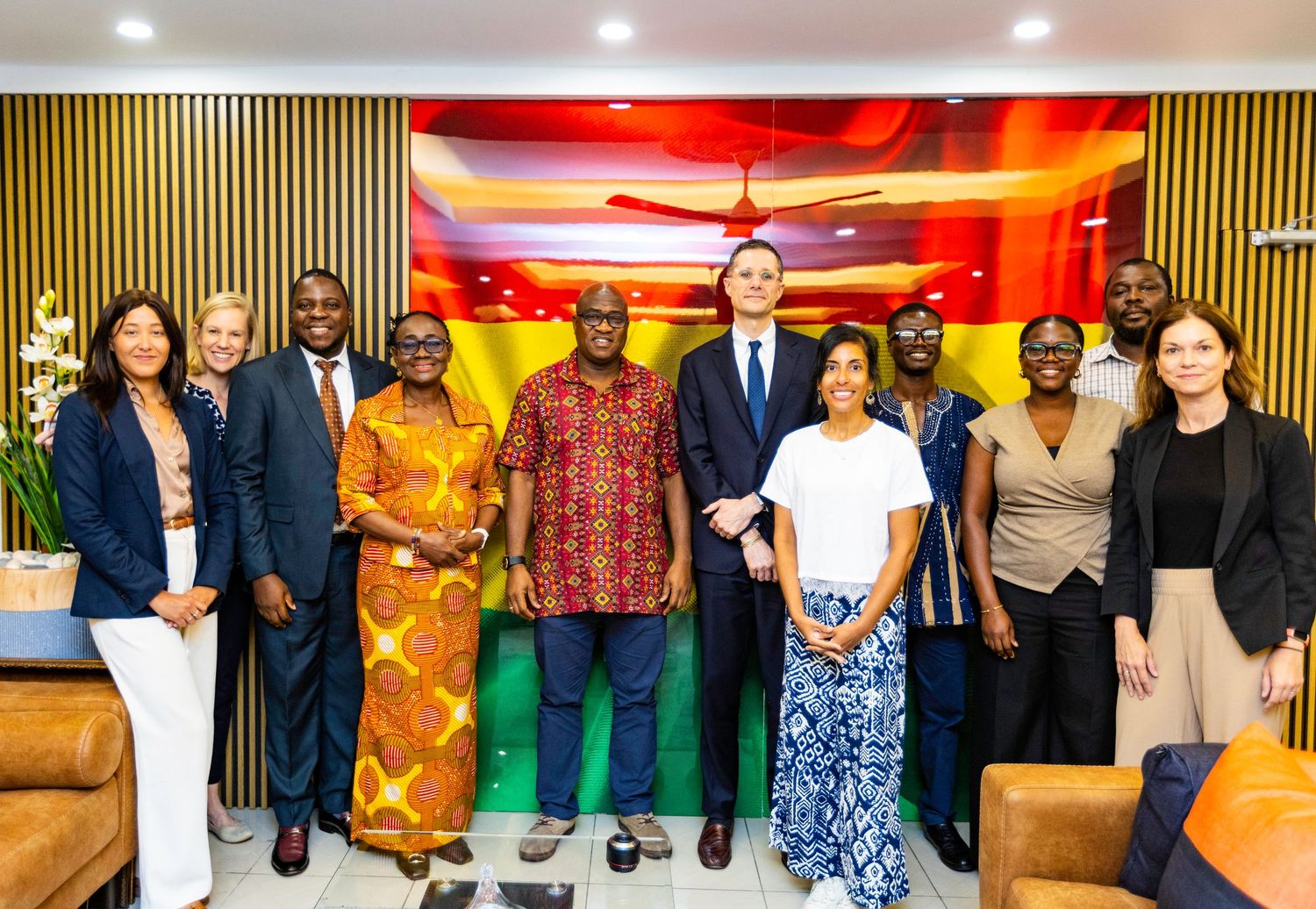 Team members pose for group photo in office setting with vibrant red ceiling lighting.