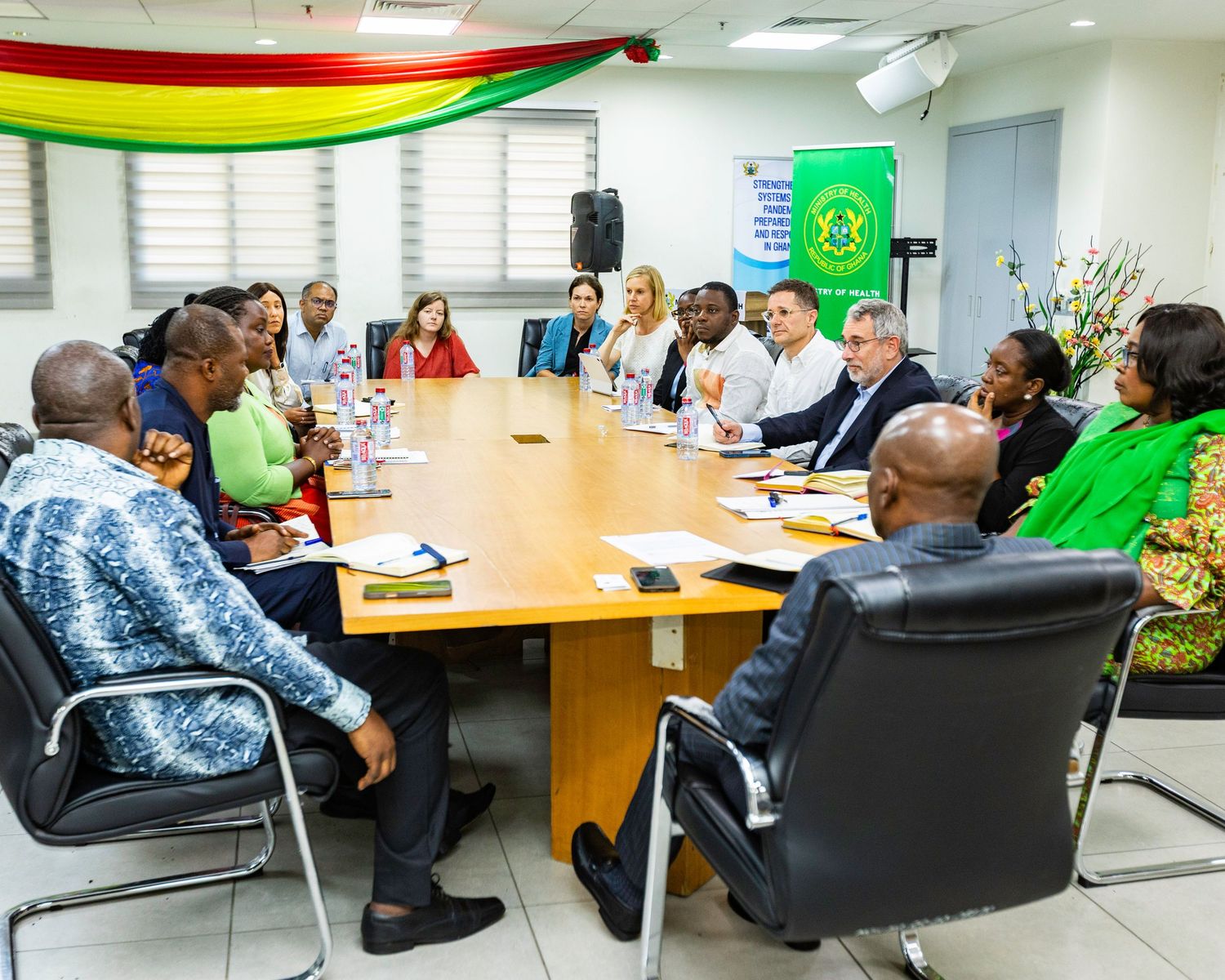 Large group meeting in conference room with Ghana-themed decorations and round table setup.
