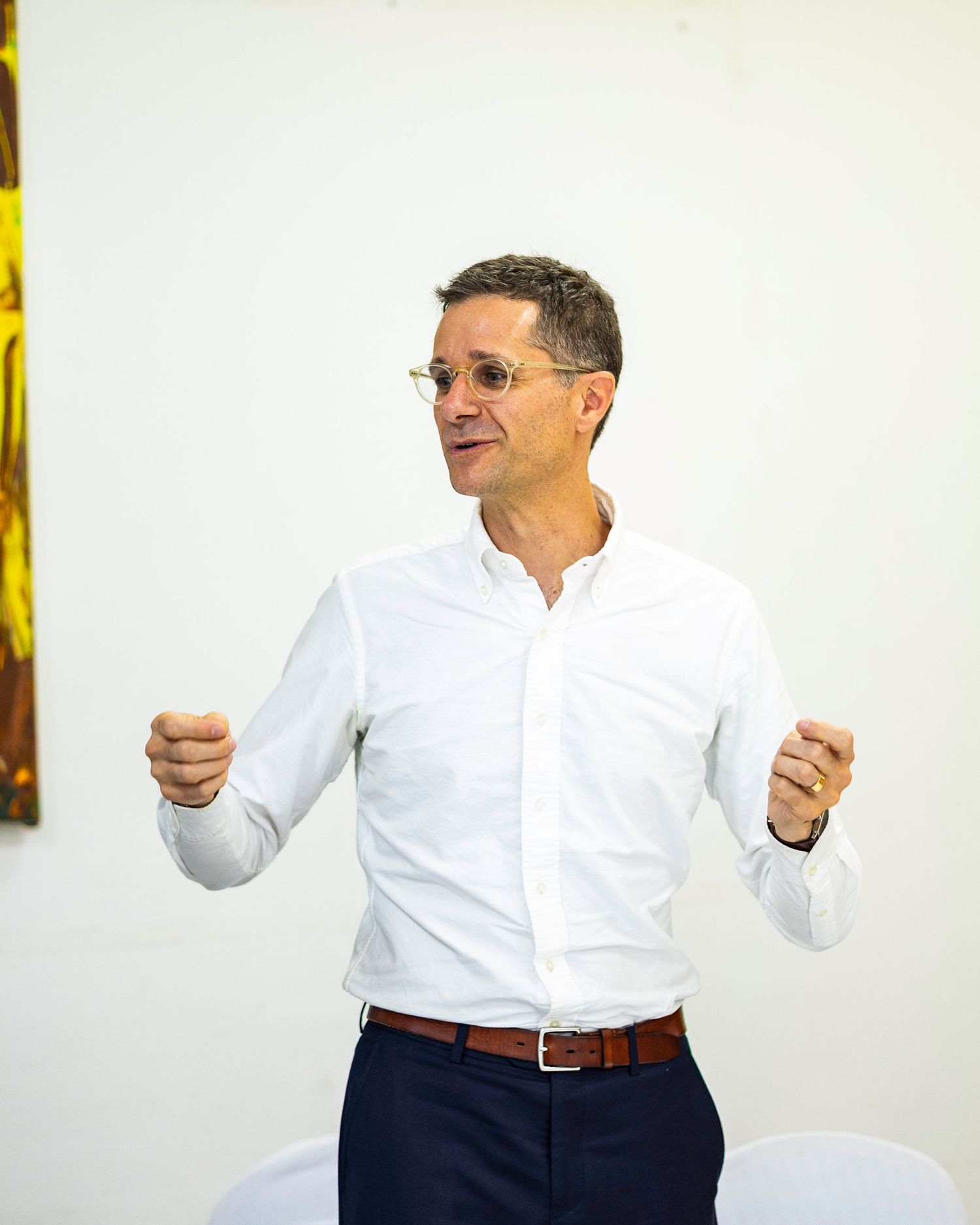 Professional speaker in white button-down shirt gesturing during presentation.