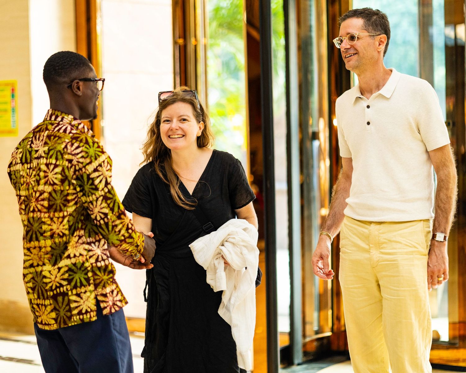 Group of professionals walking through a bright hallway with large windows.