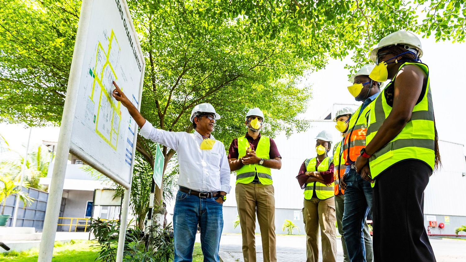 Construction team reviewing site plans and blueprints outdoors wearing safety gear.