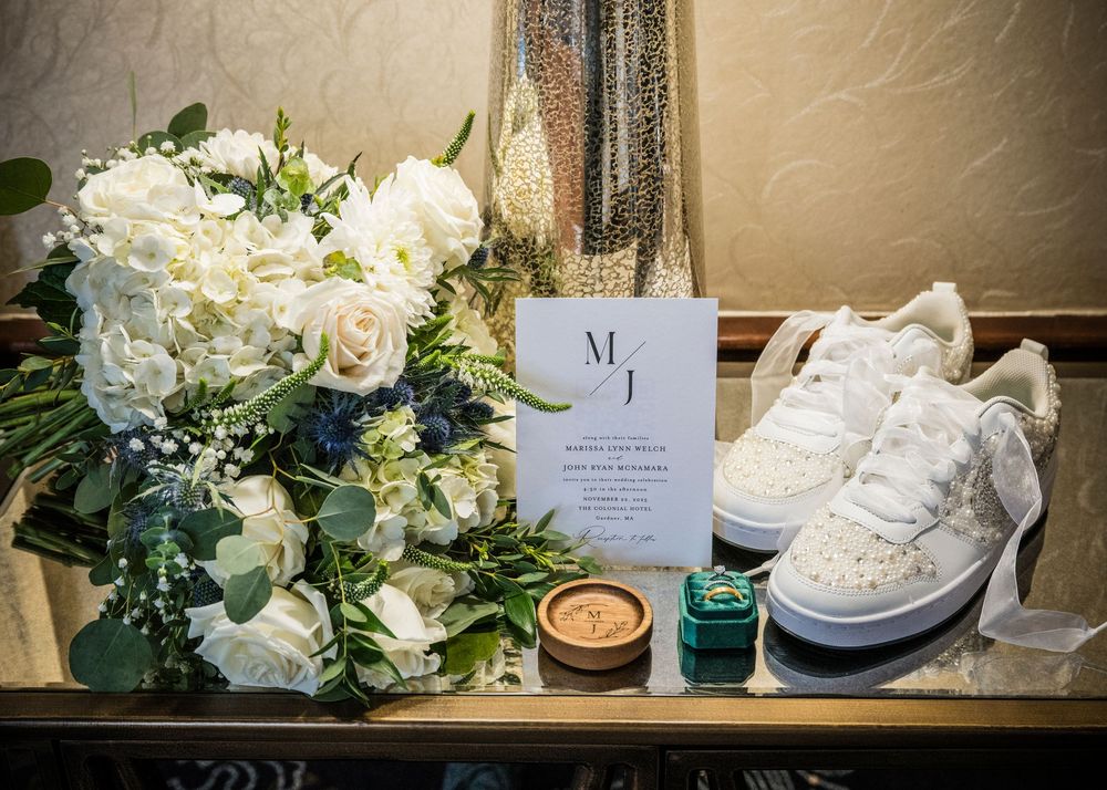 Wedding details featuring white floral arrangements, shoes, and monogrammed decor on display.