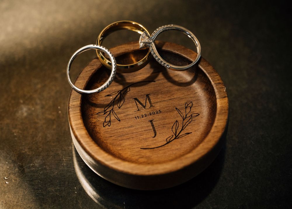 Three wedding rings arranged on a wooden ring holder with decorative engraving.