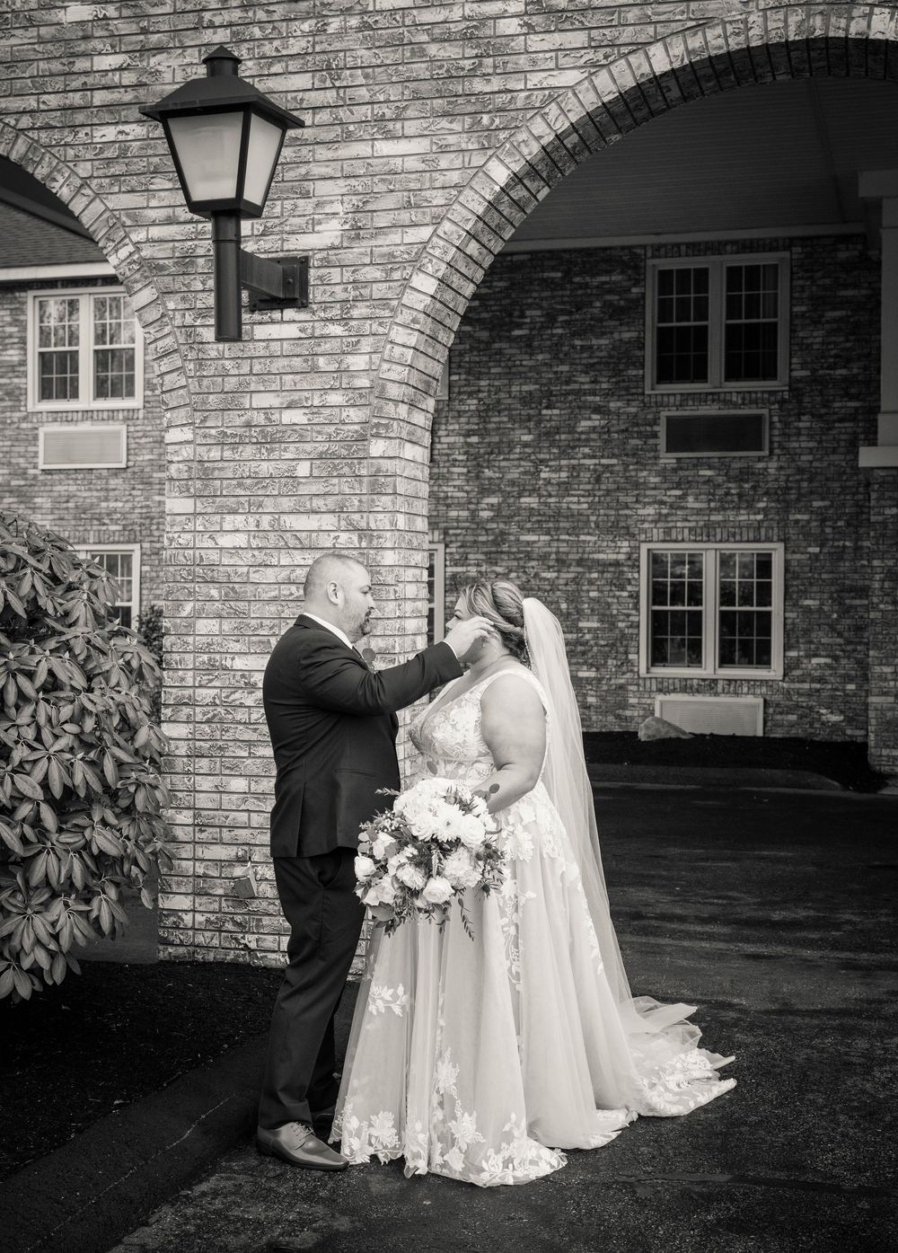 A series of romantic black and white wedding photos showing a couple embracing against a stone building exterior.