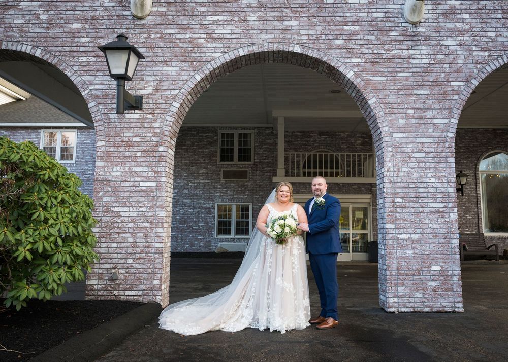 A romantic wedding couple poses under brick archways with classic architectural details.