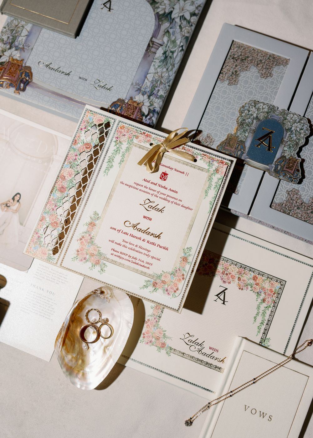 Wedding invitations and stationery laid out on white surface with delicate floral designs and gold accents.