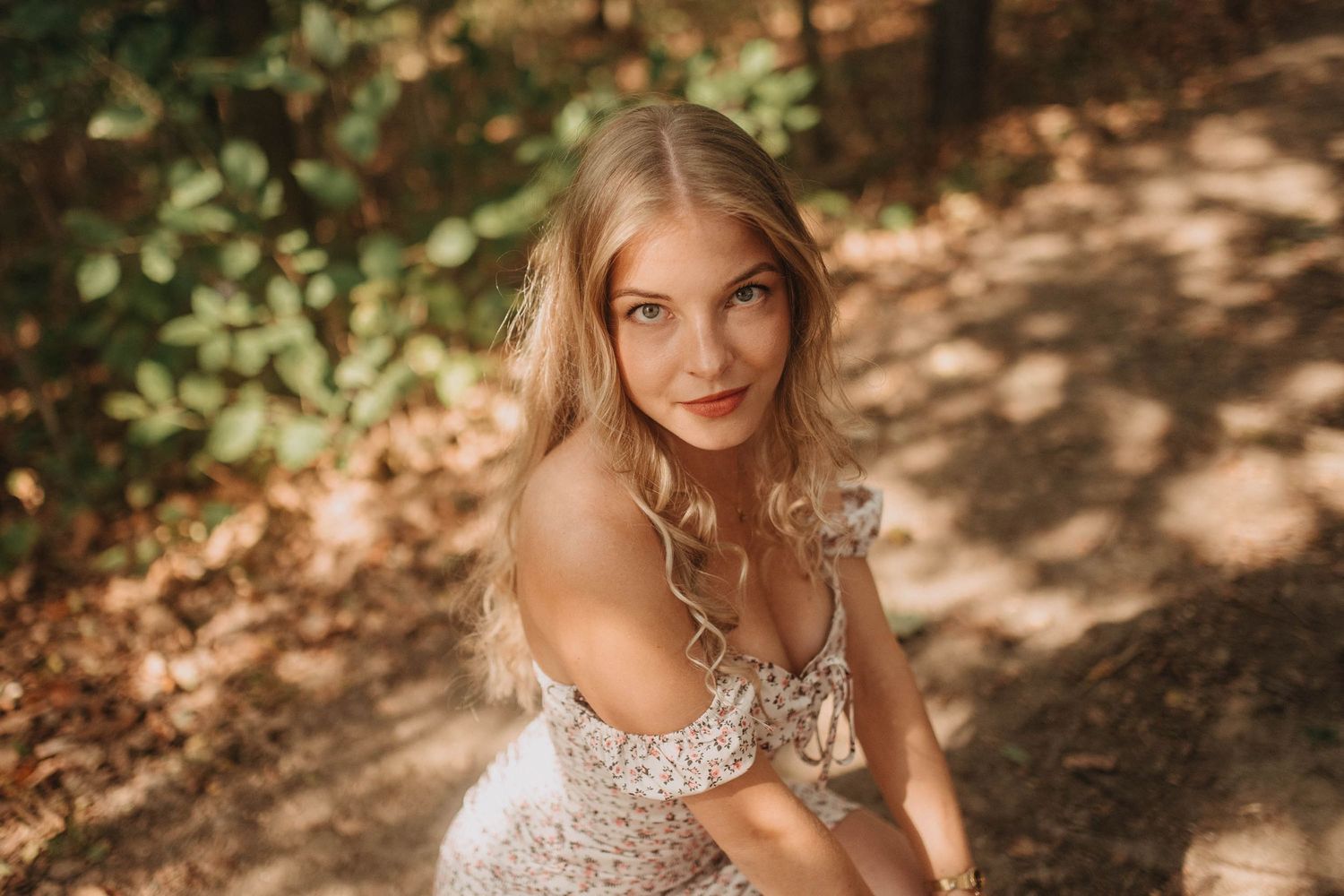A dreamy forest photoshoot featuring a sparkly off-shoulder dress in dappled sunlight.