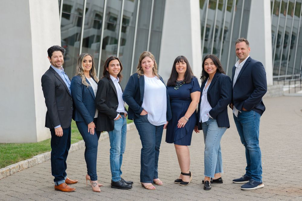 Group of people in business attire and casual clothing standing in a line outside a modern building.