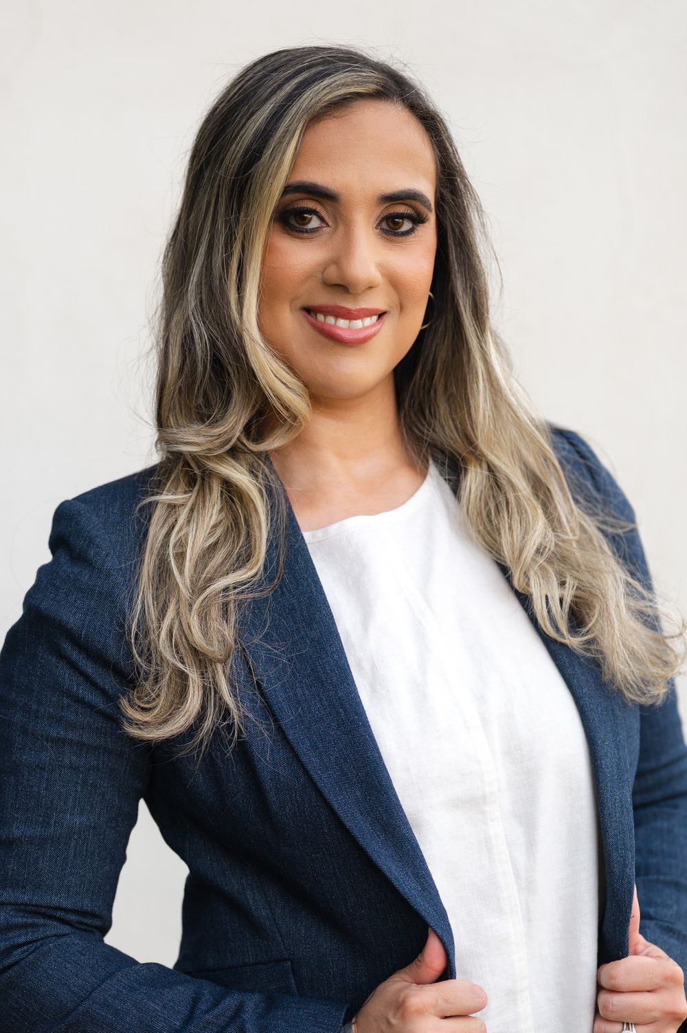 Professional headshots showing a person in a navy blazer and white top with silver-toned hair against a light background.