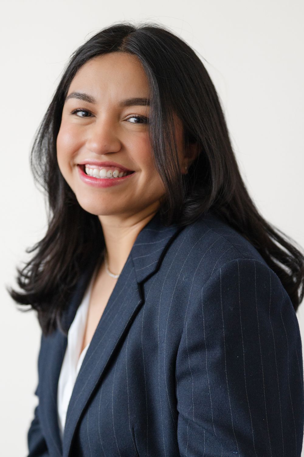 Professional headshots of a woman in a navy blazer smiling against a white background.