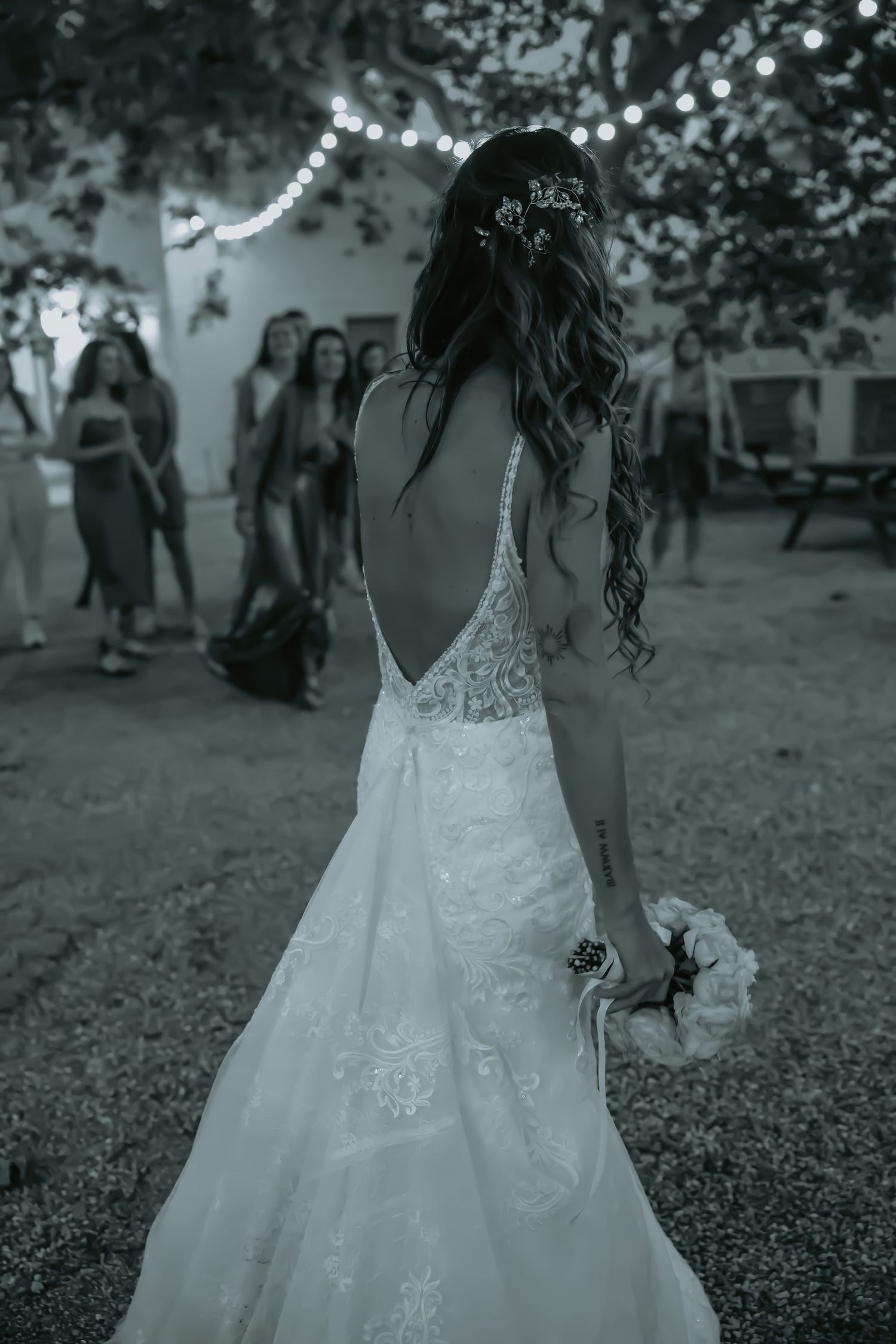 Black and white photo of bride in lace dress during outdoor wedding reception.